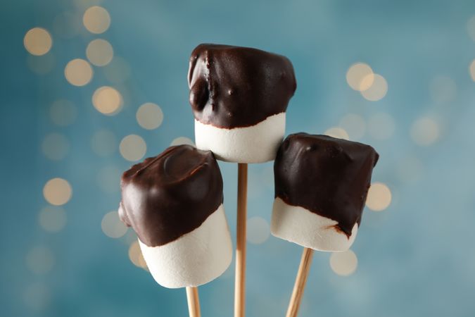 Marshmallow in chocolate against blue background with blurred lights