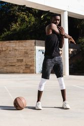 Black sportsman stretching on basketball court