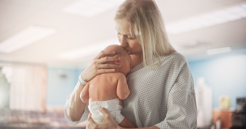 Young Happy Mother Holding Her Newborn Child, Bonding with Little Infant in Modern Maternity Hospital.