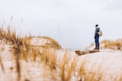 Man walking between sand field with dry grass