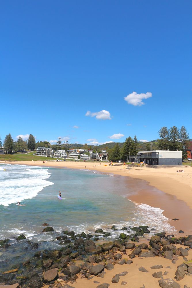 Beachside view of peaceful coastline with gentle waves and blue sky during sunny day
