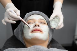 Young woman cream mask facial in beauty clinic.