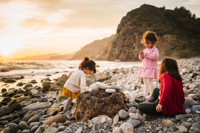 Cute girls resting on stony beach in evening
