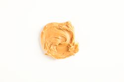 Creamy peanut butter isolated on bright background, top view. A traditional product of American cuisine