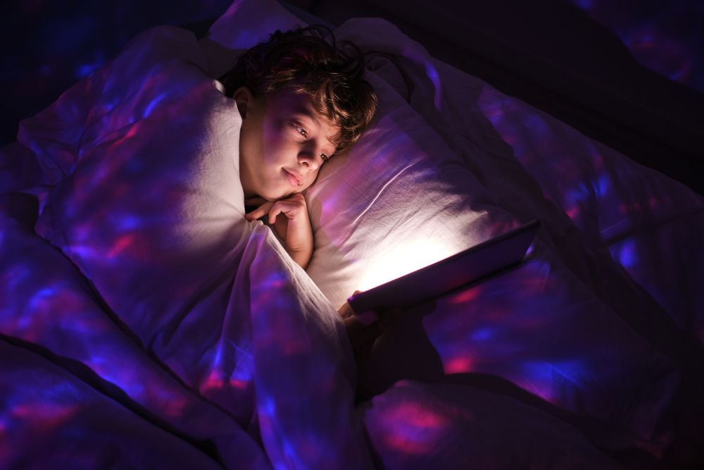 Boy browsing tablet in dark bedroom