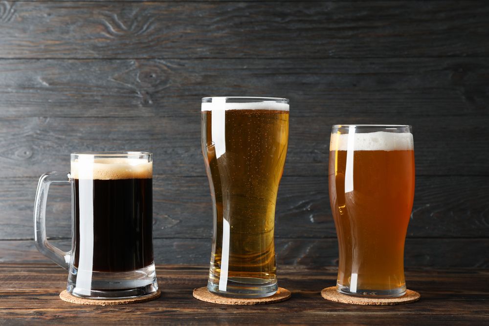 Different mugs with beer on wooden table, copy space