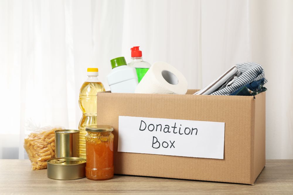 Donation box with different food on wooden table. Volunteering