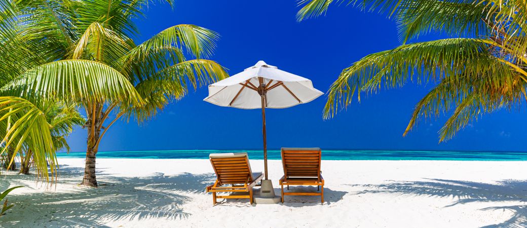 Lounge chairs and parasol on a tropical beach, wide shot