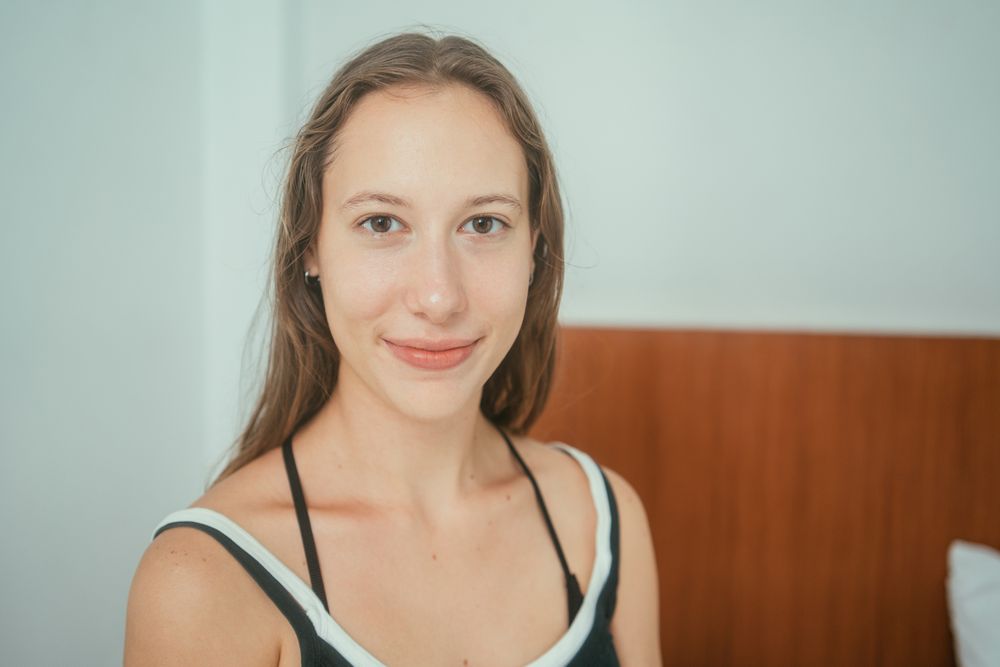 Woman sitting on bed smiling at camera