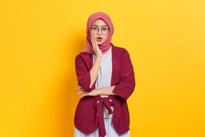 Curious woman in red headscarf and glasses looking at camera