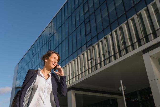 Smiling entrepreneur browsing smartphone outside office building