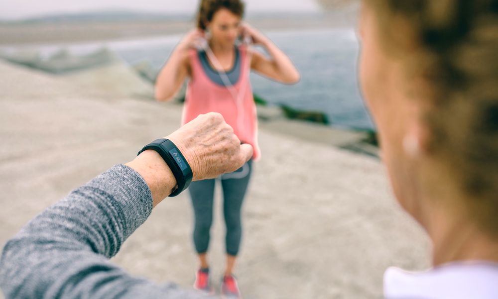 Older woman looking smart watch with female coach