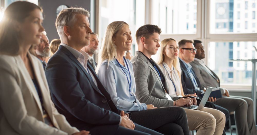 Woman Sitting in Crowded Audience at Human Resource Forum.