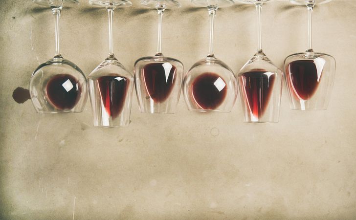 Glasses of red wine glasses laying on grey background, wide composition, with copy space