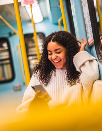 Smiling Black woman using smartphone in transport