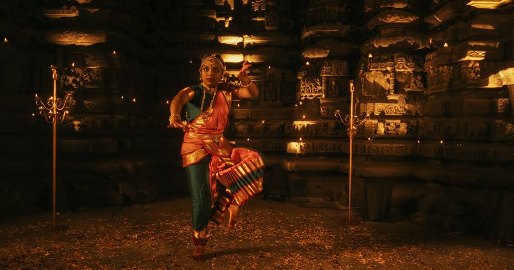 Young Indian Woman Dressed in Traditional Colorful Sari Gracefully Performs Bharatanatyam Dance in a Temple.