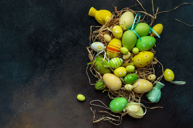 Top view of colorful Easter decorations in straw on grey table