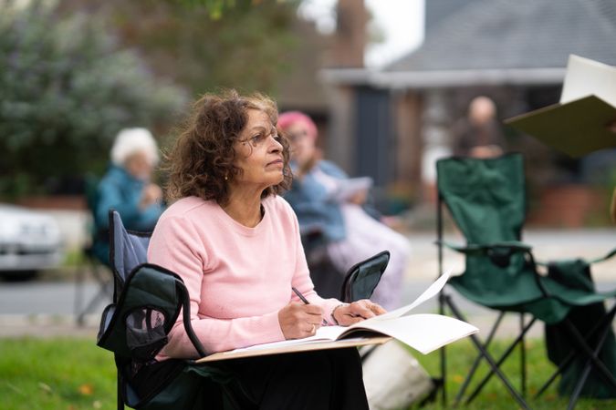 Indian woman looking up while drawing during outside art class