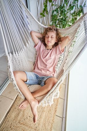 Cute child resting in hammock on balcony