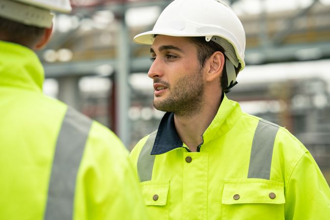 Engineer worker in protective uniform talking with colleagues at construction site