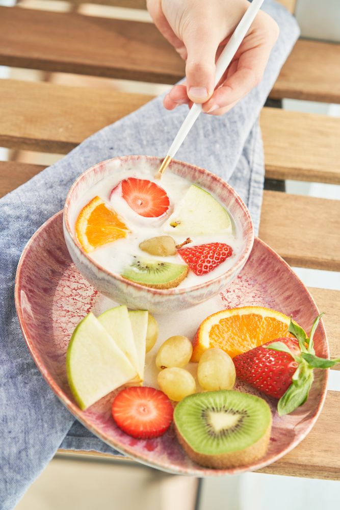 Faceless person dipping strawberry into yogurt