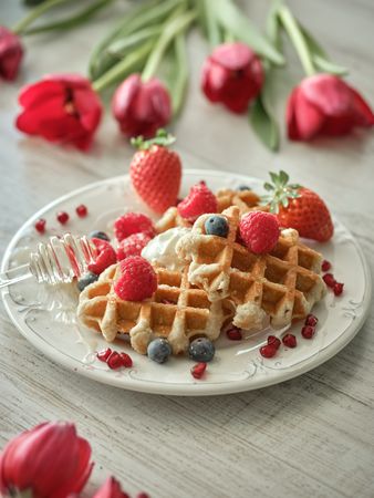 Sweet waffles on table with tulips