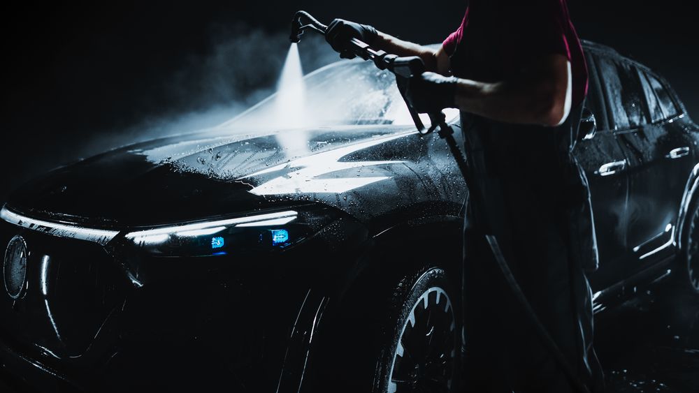 Modern Electric SUV with LED Headlights is Being Cleaned at a Dealership Car Wash.