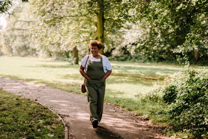 Mature woman walking on path in green park