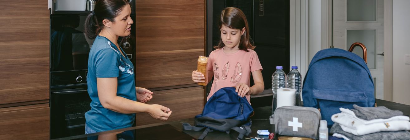 Mother explaining to her daughter how to prepare an emergency ba