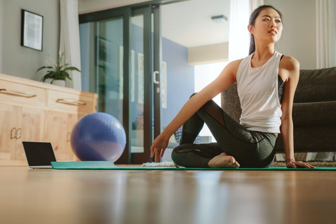 Healthy woman sitting on exercise mat and doing yoga