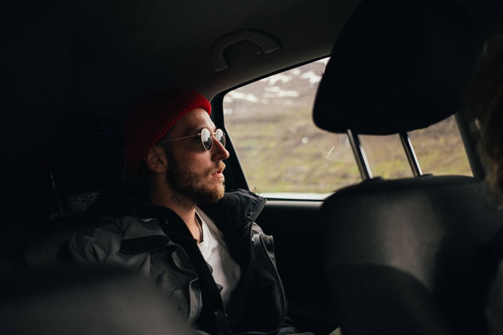 Male in sunglasses observing scenery from vehicle window
