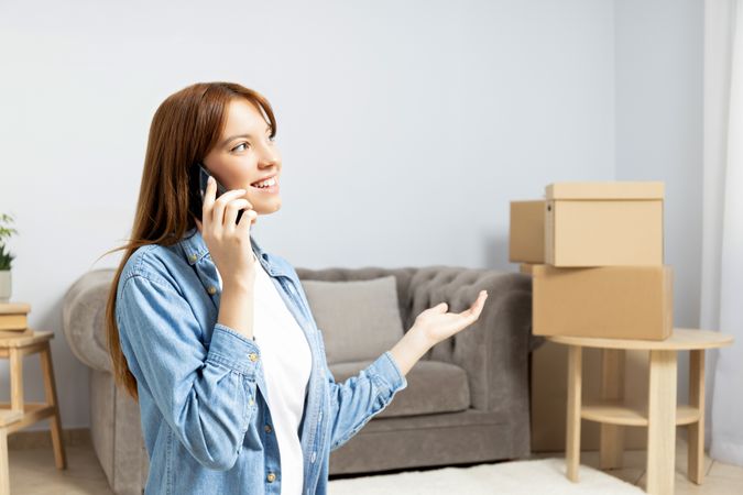 Moving concept, woman talking on the phone with boxes in the background.