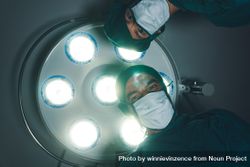 Two doctor looking down from light in a hospital’s operation room 0Lk3Rb