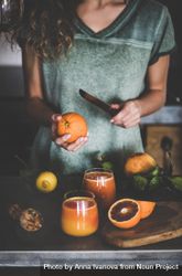 Woman holding knife with freshly squeezed blood orange juice bGEna5