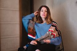 Charming woman in sweater sitting near wall
