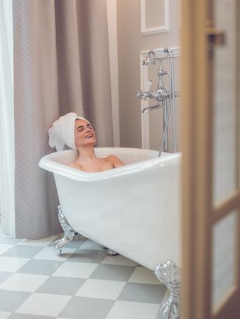 Happy woman resting in bathtub