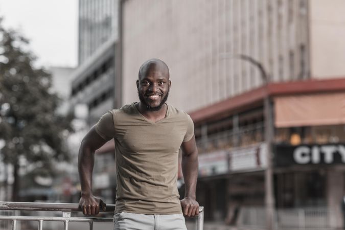 Man in gray shirt standing beside rail on street