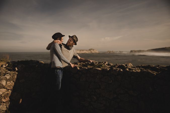 Man holding woman on hands near stones on shore