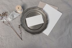 Blank greeting card on plate with dry flower and craft paper envelope