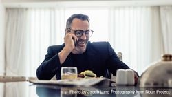 Businessman having lunch and talking on phone in hotel room 5RWqB4
