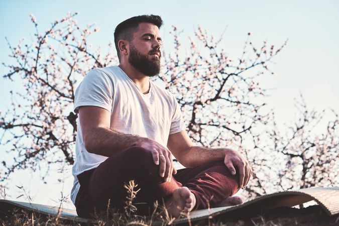 Bearded man meditating in spring garden