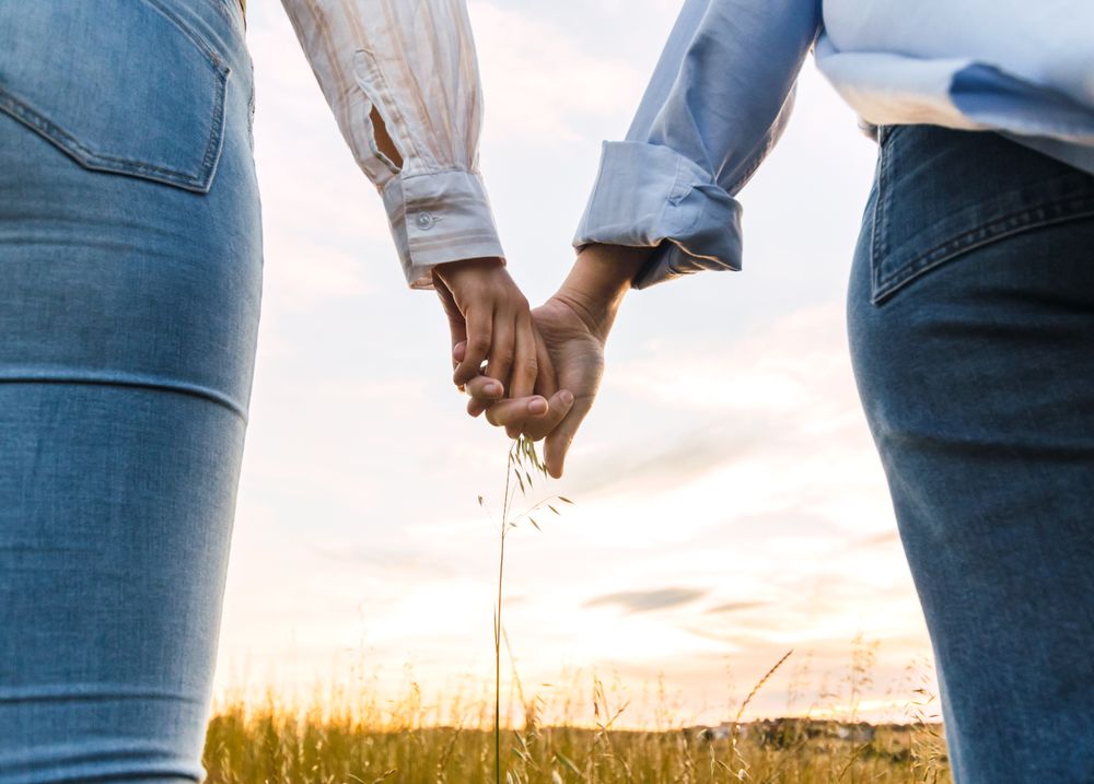 couple holding hands on a beautiful field at sunset