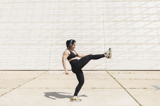 A woman kicks her leg in the air while enjoying some time in the sun after exercising