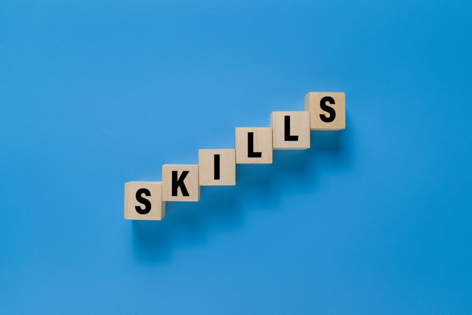 male hand put wooden blocks with skills words isolated on blue background