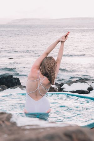 Woman sitting in pool near stones