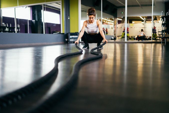 Woman working out upper body close to the ground with ropes in gym