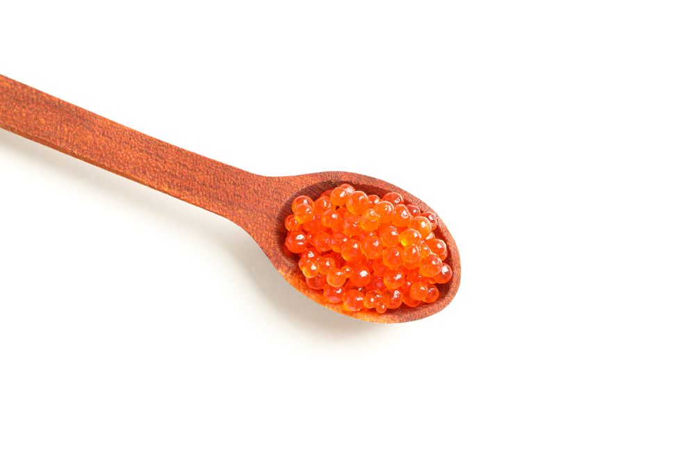 Spoon with red caviar isolated on blank background, top view