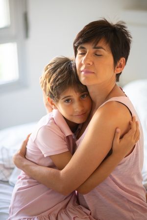 Mother and child hugging dressed in light pink