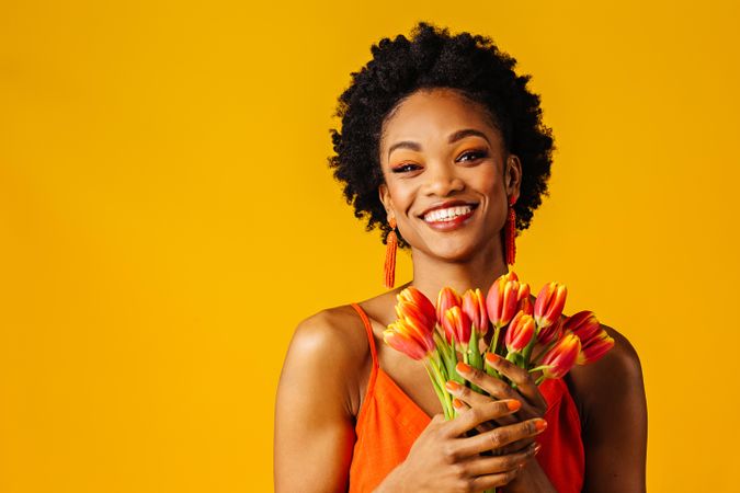 Portrait of happy Black woman holding bouquet of tulips