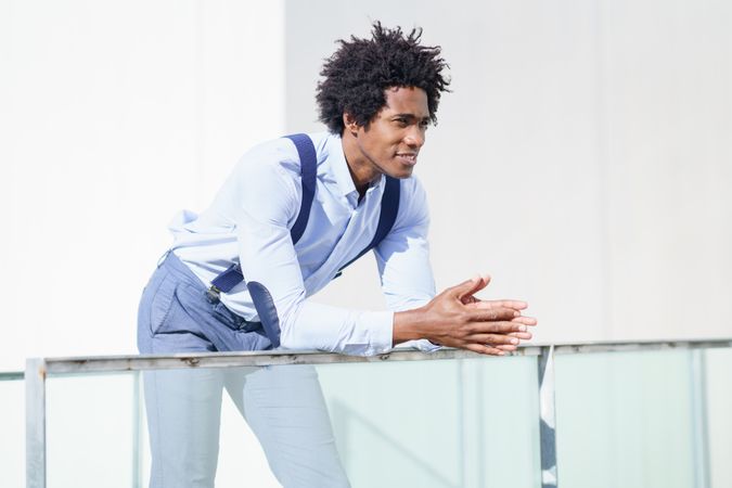 Man wearing business casual leaning on railing outside